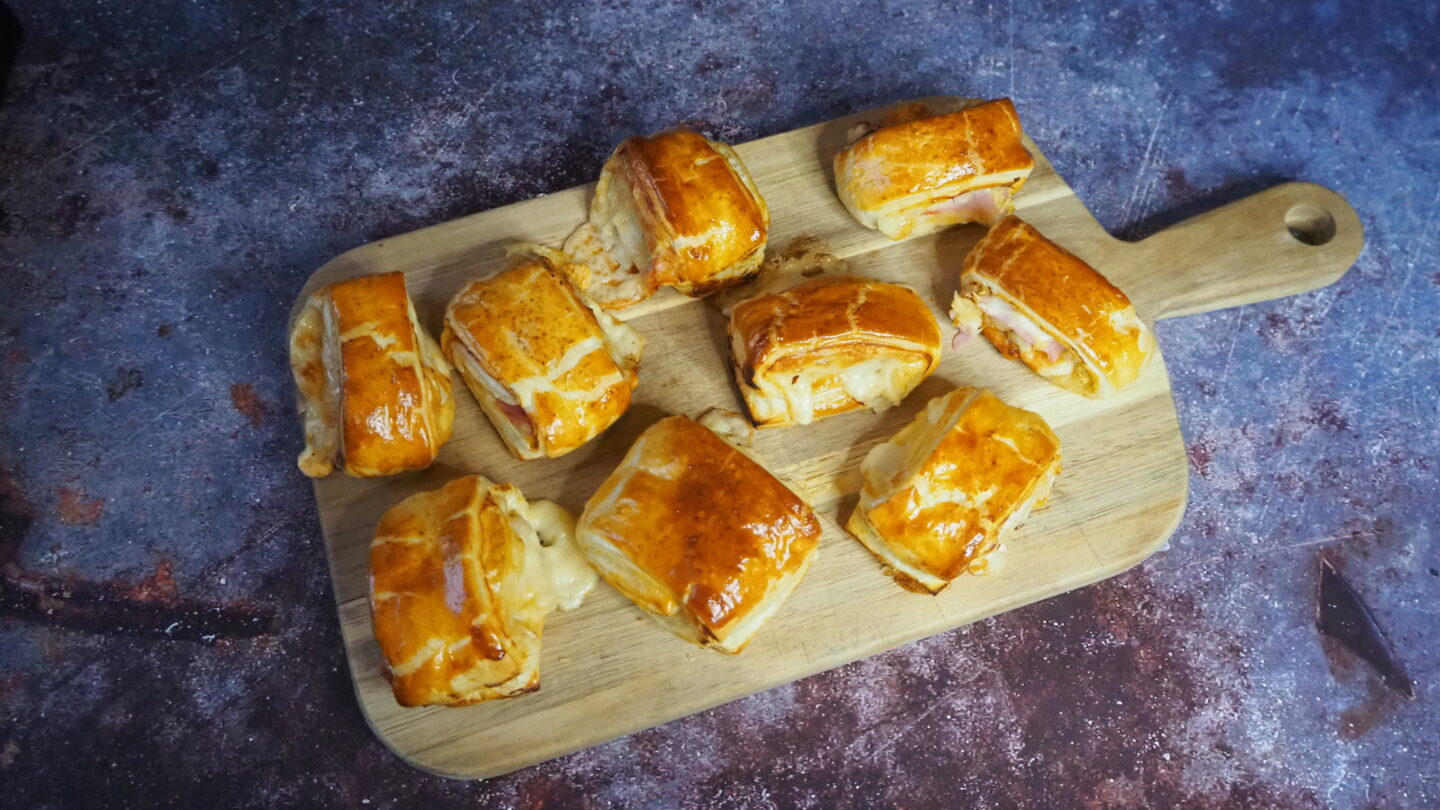 Cutting board with croque monsieur puff pastry rolls on a space like background