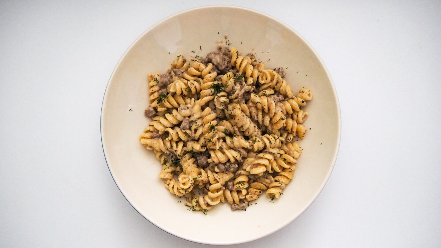 Beef Stroganoff made with hamburger meat and fusilli in a white bowl on a white background