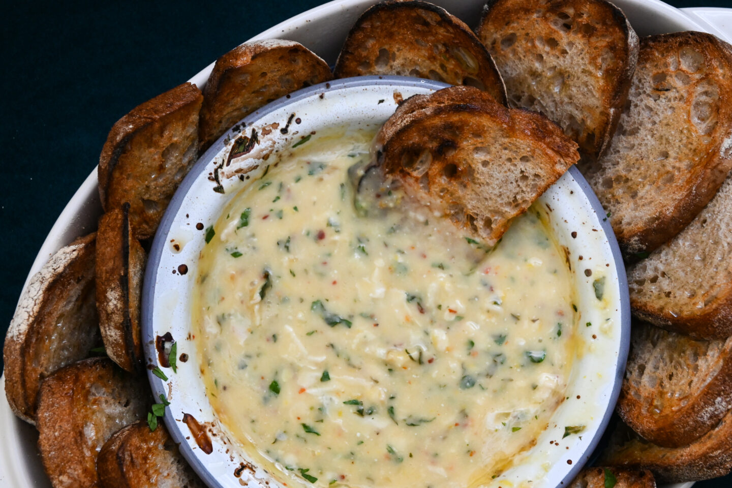 Enamel bowl with dip made from baked camembert, herbs and oil & lemon juice served with sliced bread