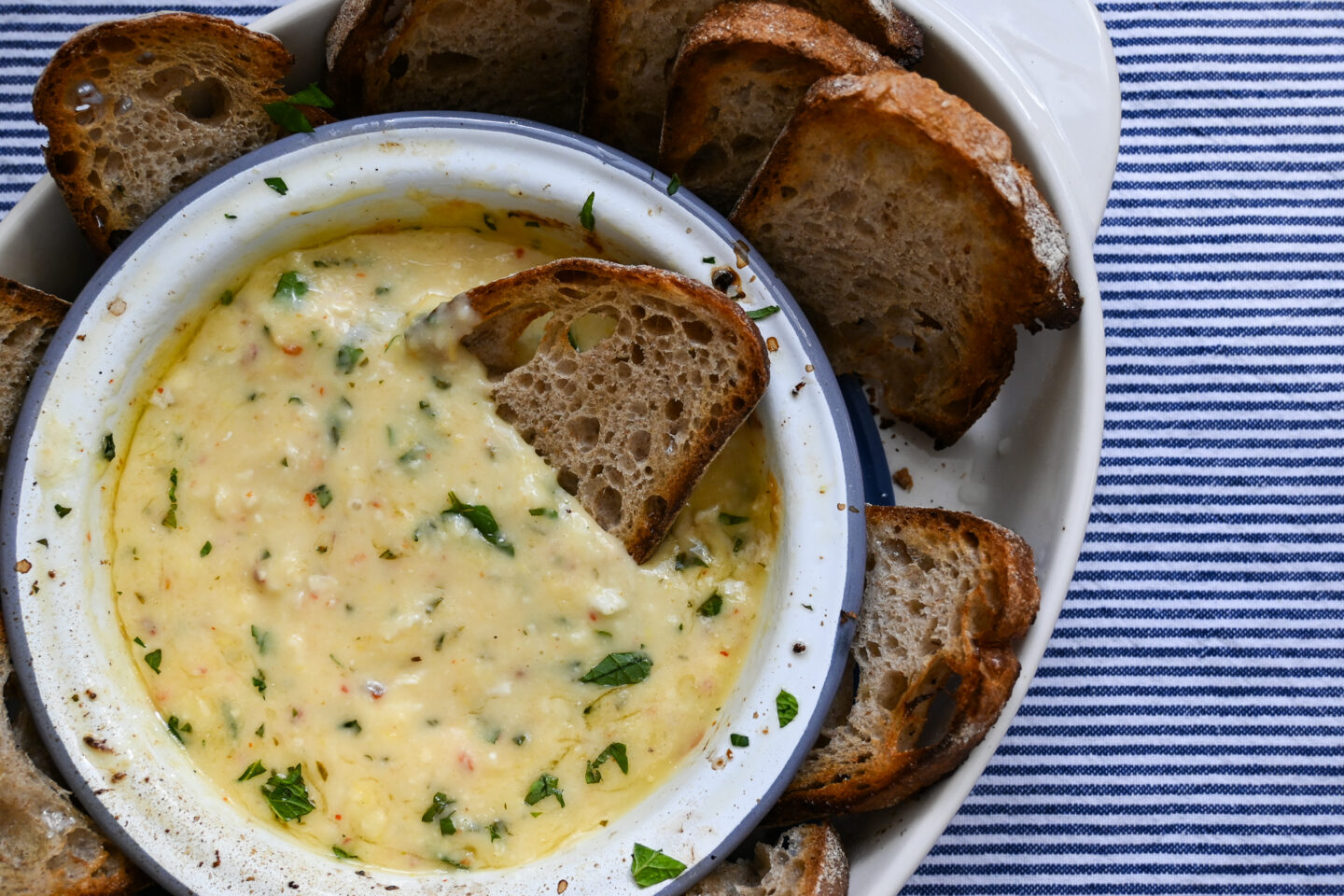 Enamel bowl with dip made from baked camembert, herbs and oil & lemon juice served with sliced bread