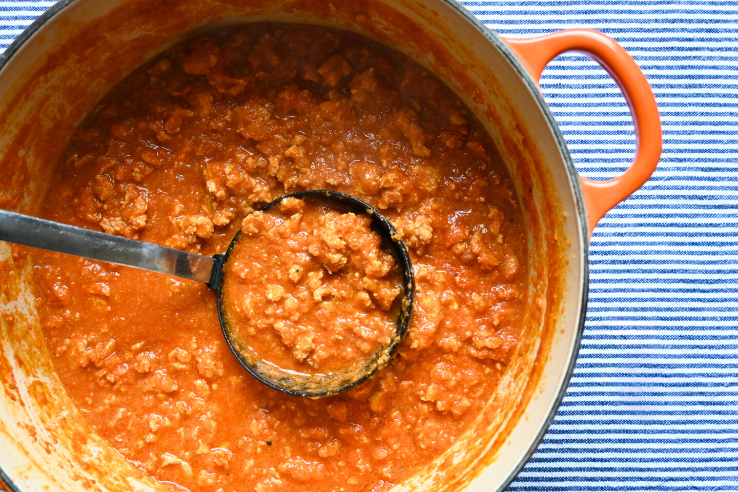Chicken Bolognese Sauce in a large casserole with a ladle