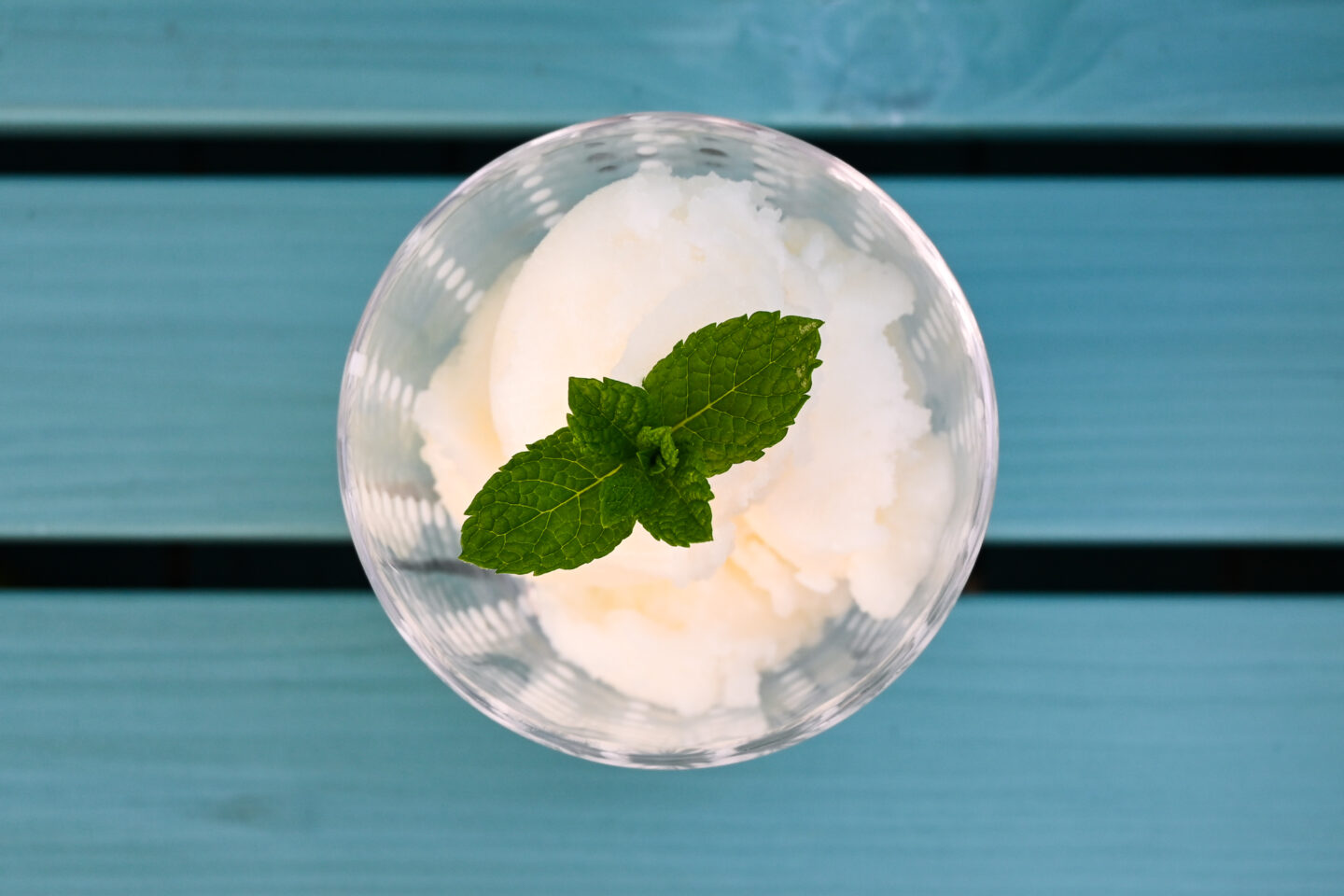 Fizzy Lemon sorbet from the top with a view of the mint leaf garnish on a turquoise slatted wood background