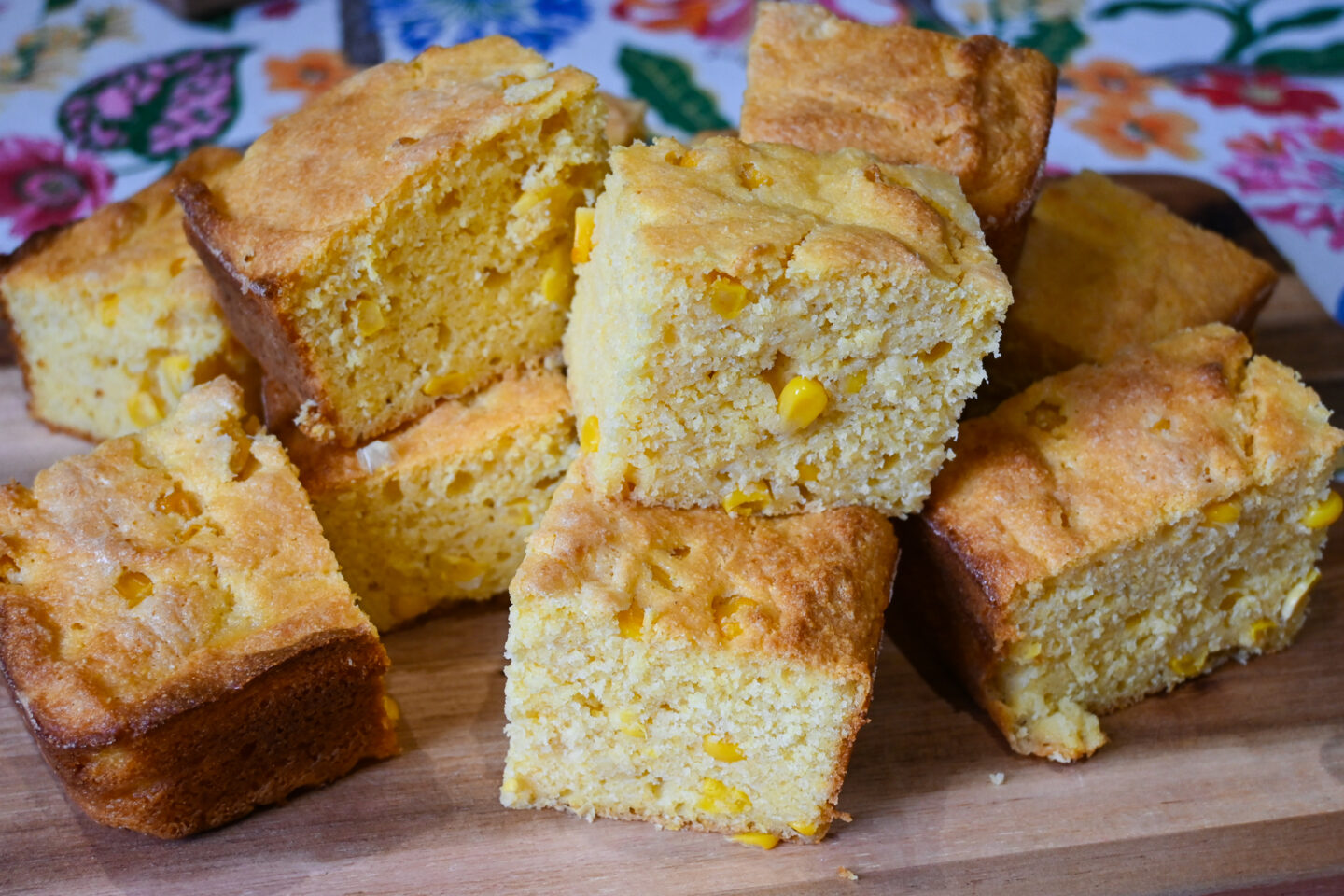 Squares of cornbread on a cutting board with corn kernels in the actual bread