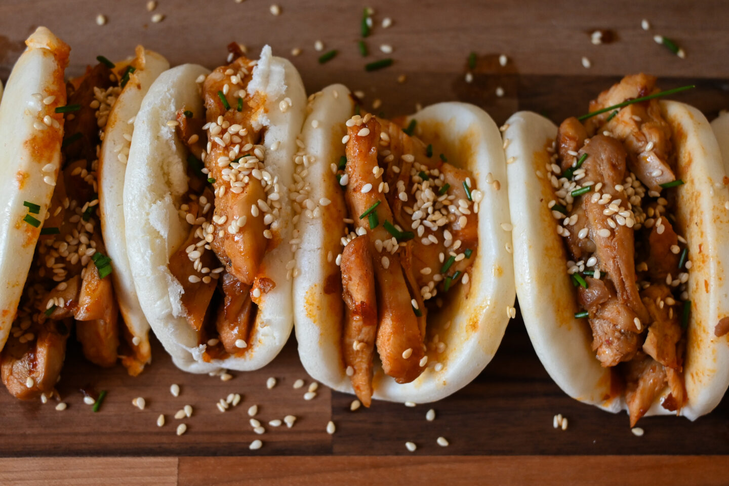 Honey, Soy & Harissa Chicken Bao Buns closeup with sprinkles of chopped chives and sesame seeds