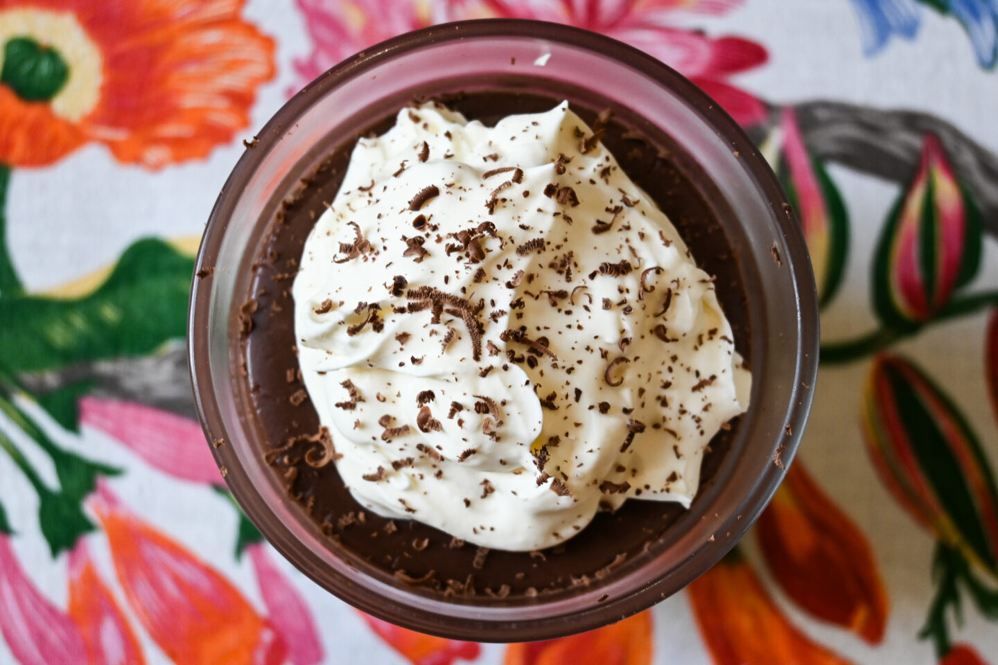 View from above of Chocolate Pudding in a small glass topped with whipped cream and chocolate shavings 