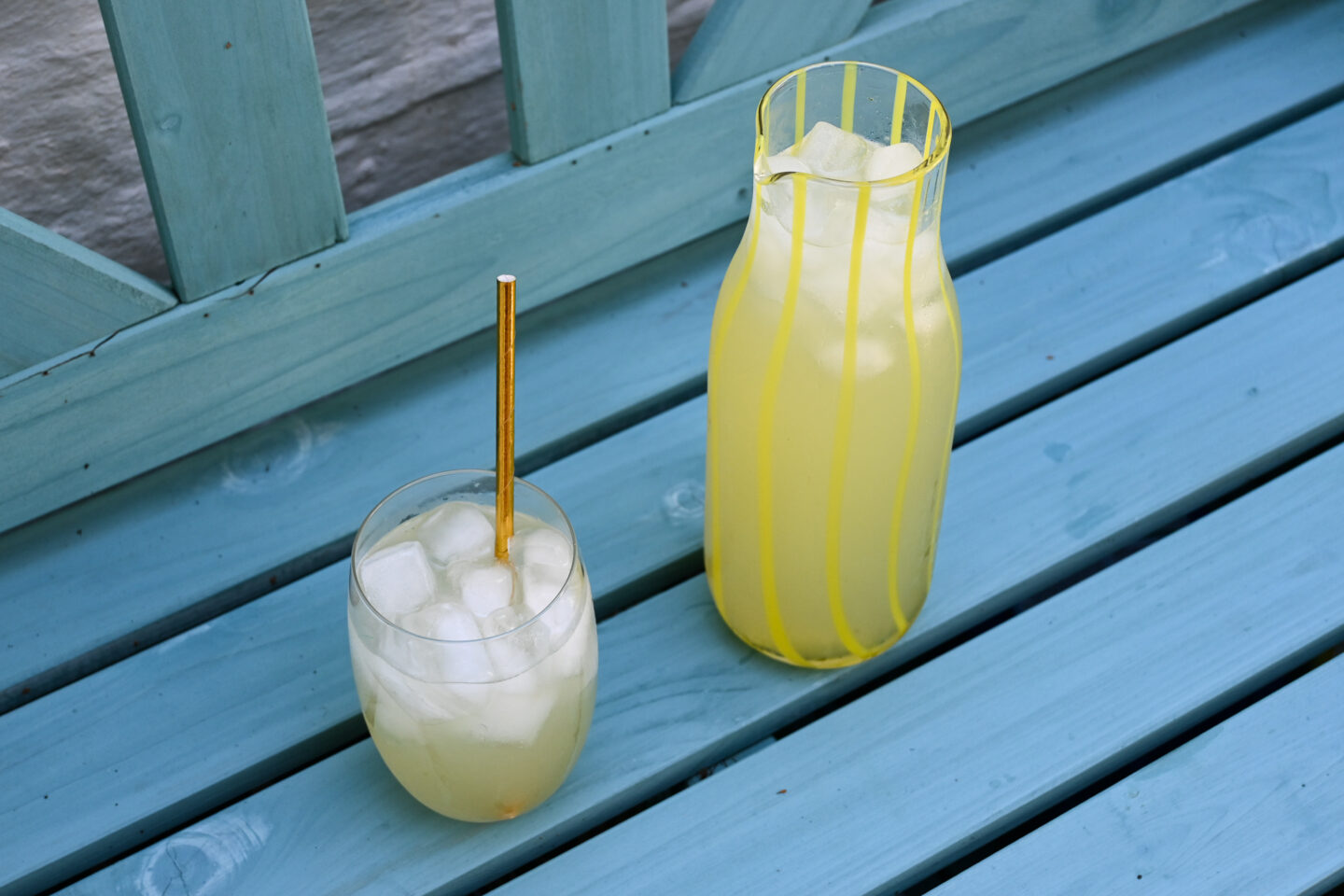 Glass & jug of lemonade on a blue wooden bench
