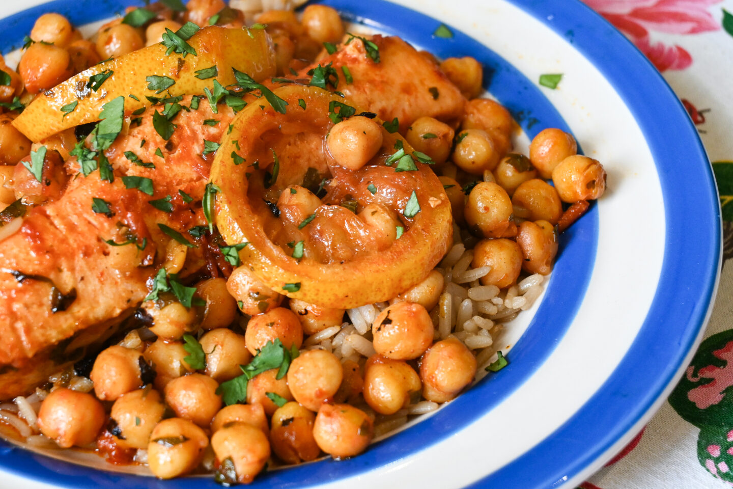 Harissa Salmon, Lemon & Chickpeas en Papillote with brown rice on a blue & white striped Cornishware plate sitting on a floral tablecloth