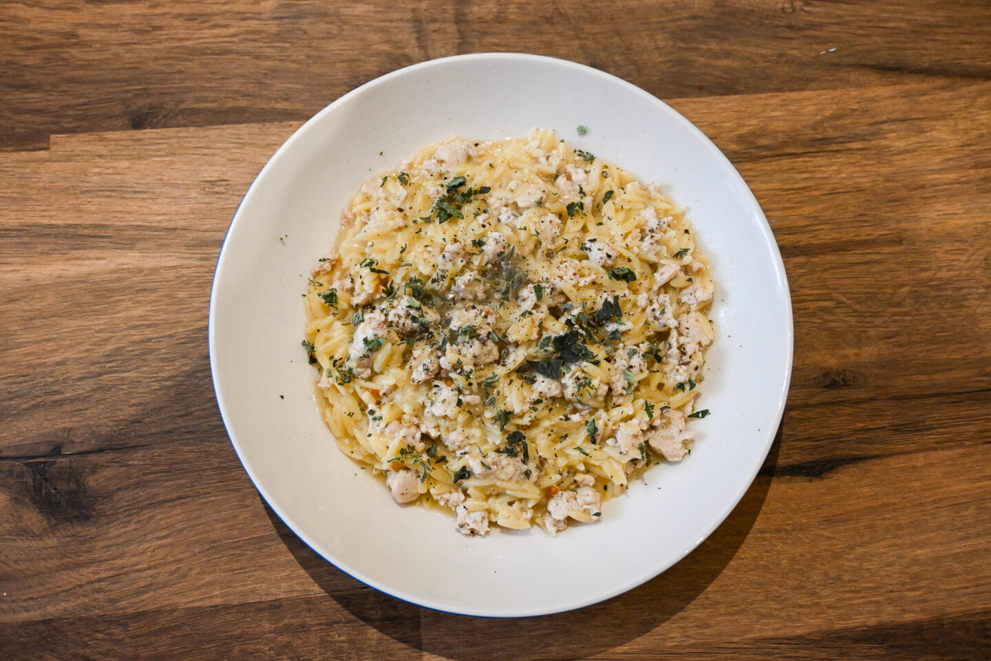 Lemon Oregano Chicken Orzo in a white Bowl on a Wooden Table