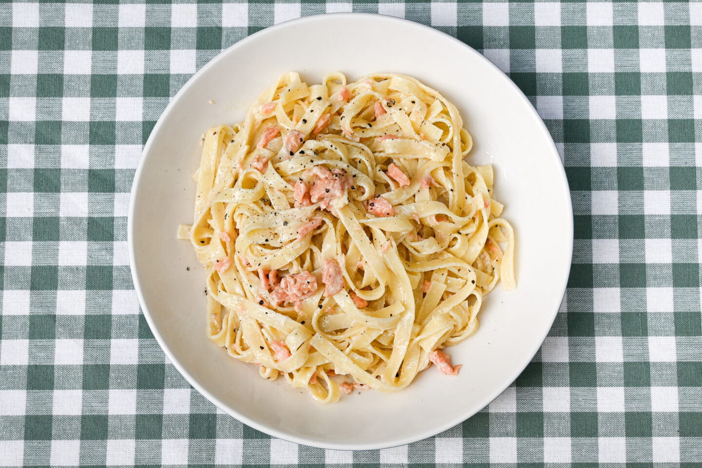 Tagliatelle with smoked salmon whisky cream sauce in a bowl on a green & white checked background