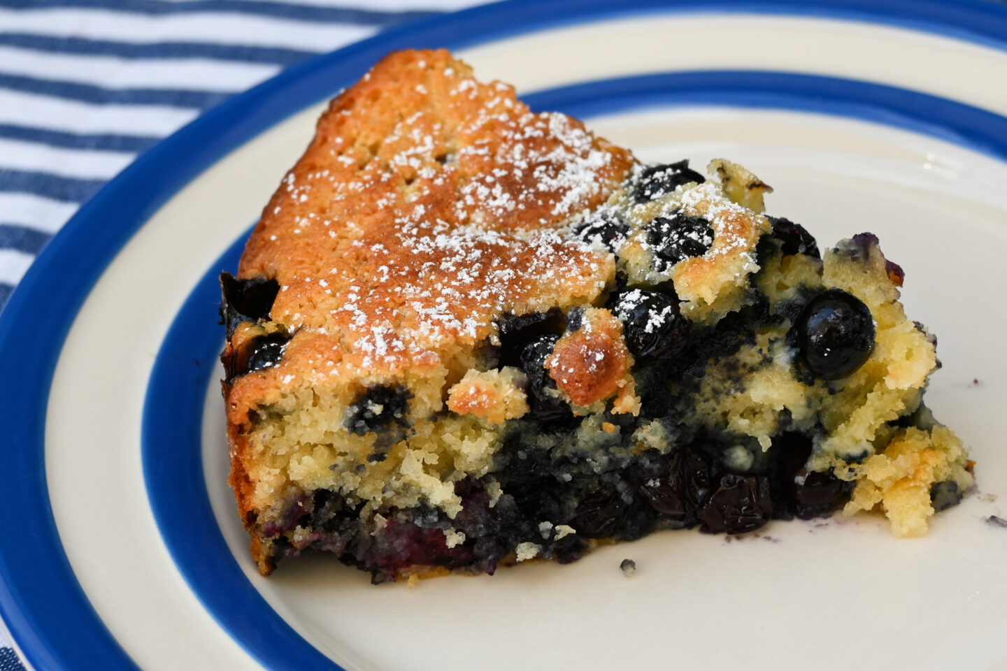 Blueberry Ricotta Cake slice on a blue & white striped plate