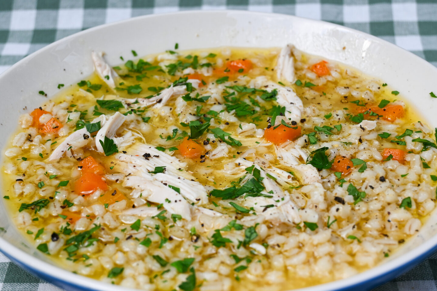 Chicken soup with barley, carrots & parsley close-up
