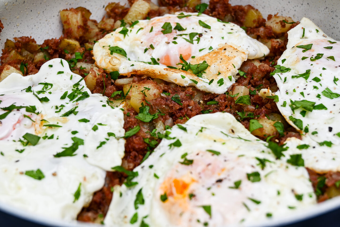 Corned Beef Hash topped with Fried Eggs and Sprinkled chopped parsley closeup