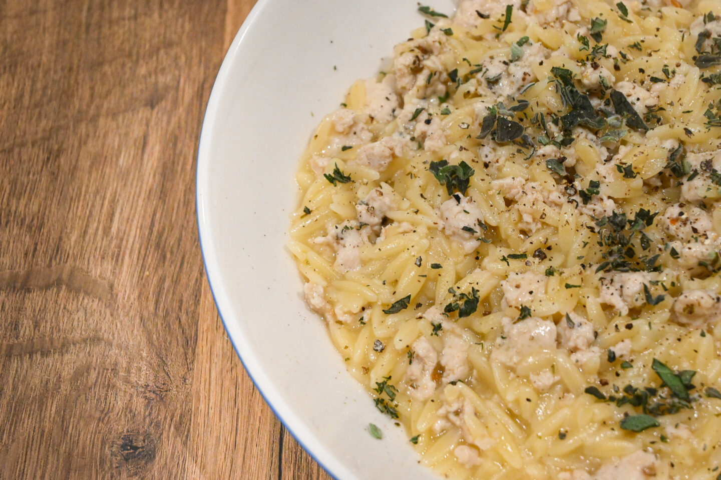 Lemon Oregano Chicken Orzo in a white Bowl on a Wooden Table