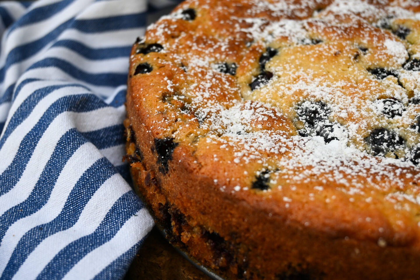 Blueberry Ricotta Cake on a blue & white striped background closeup