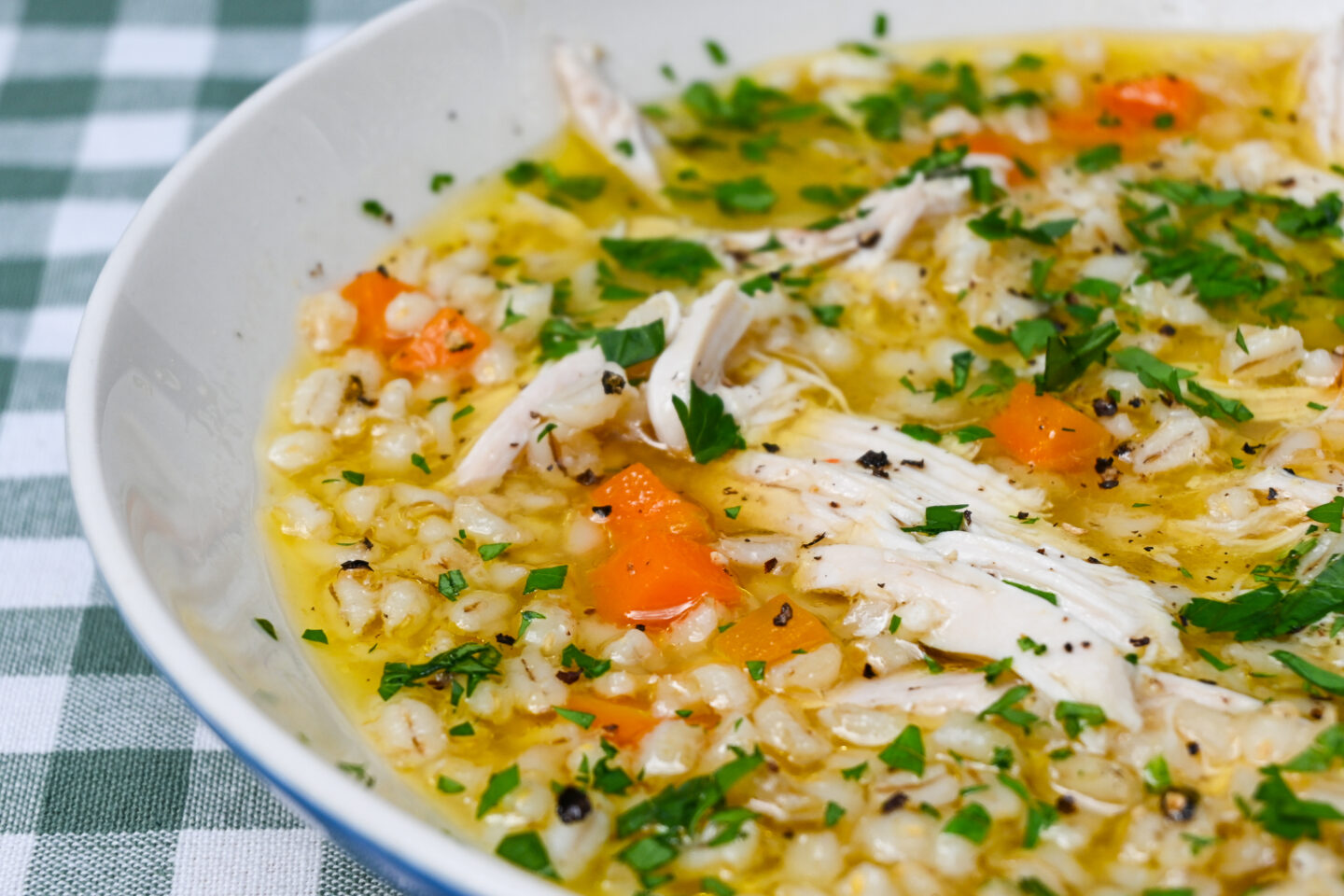 Chicken soup with barley, carrots & parsley close-up