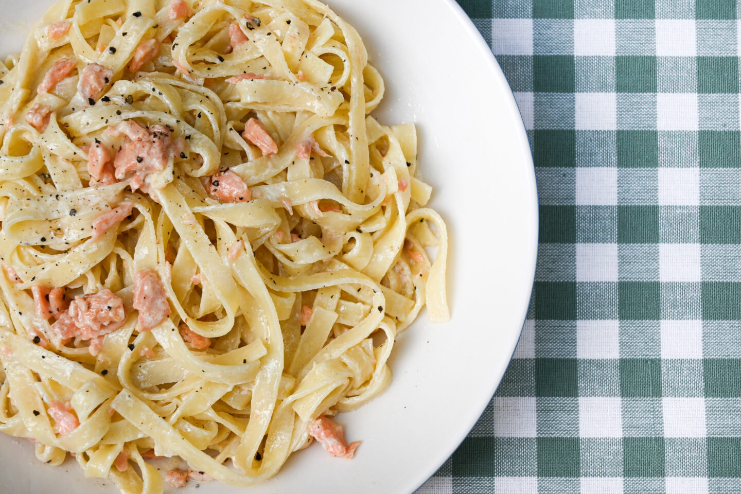 Tagliatelle with smoked salmon whisky cream sauce in a bowl on a green & white checked background