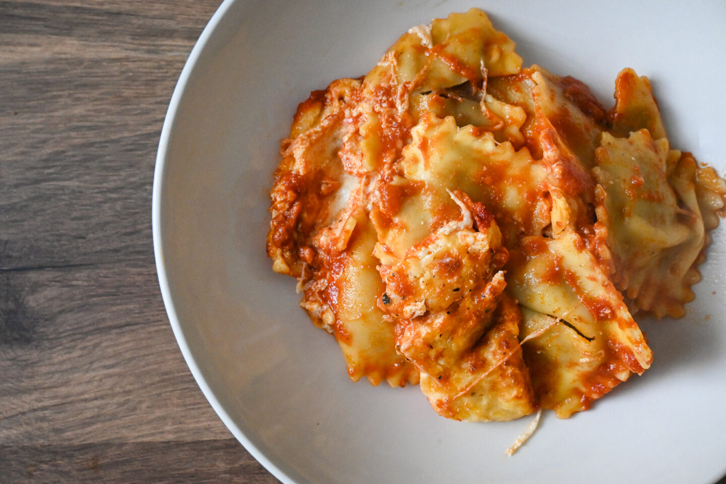 Bowl of ravioli in a tomato sauce with melted cheese