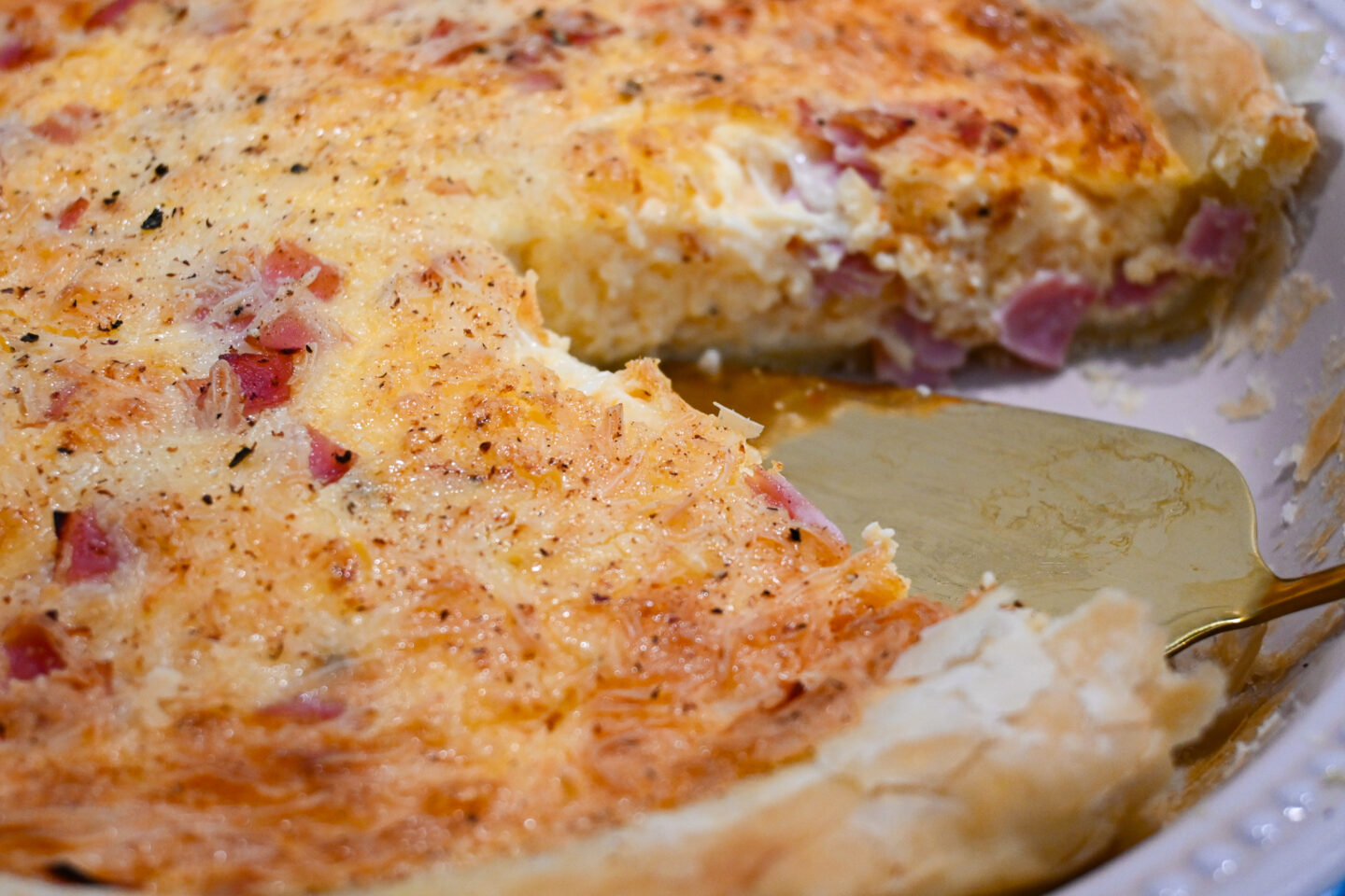 Gold serving spatula with ham & cheese puff pastry quiche