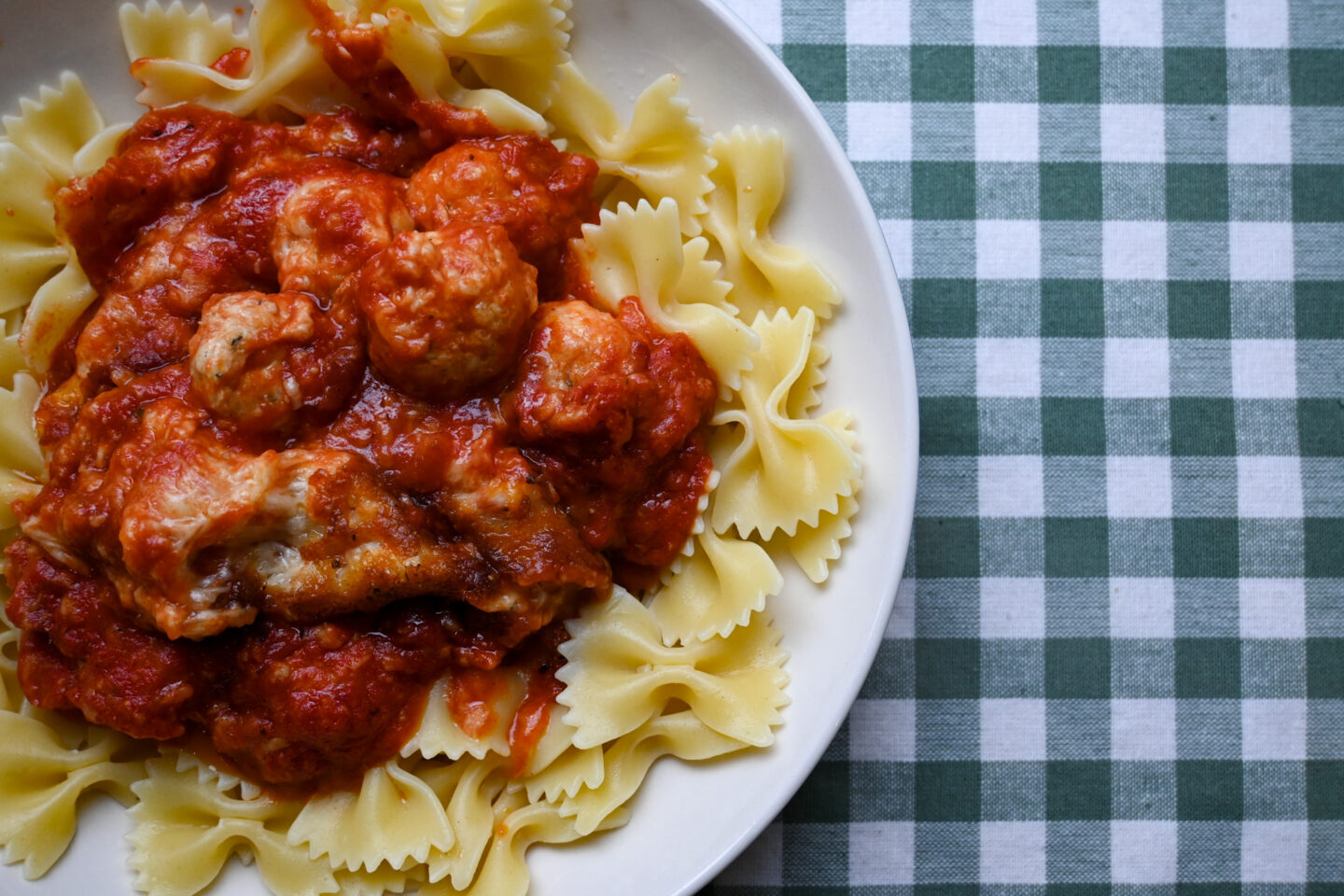 Cheesy Chicken Meatballs served atop a bed of bowtie pastaj Closeup
