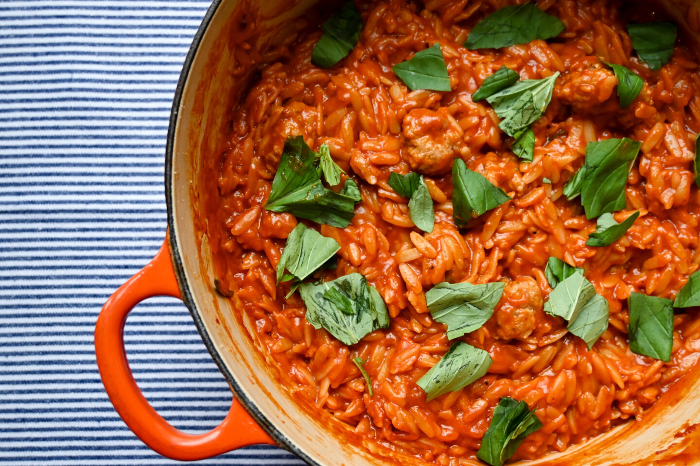 One Pot Sausages Meatballs With Orzo in a tomato sauce sprinkled with torn basil leaves