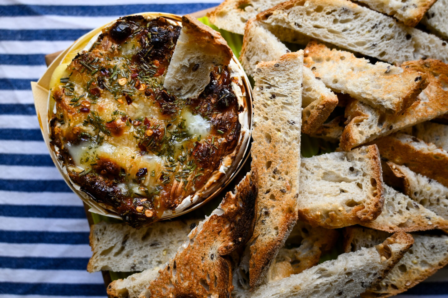 Aerial shot of Honey & Garlic Baked Camembert with toast points showing golden, blistered crust on top of cheese