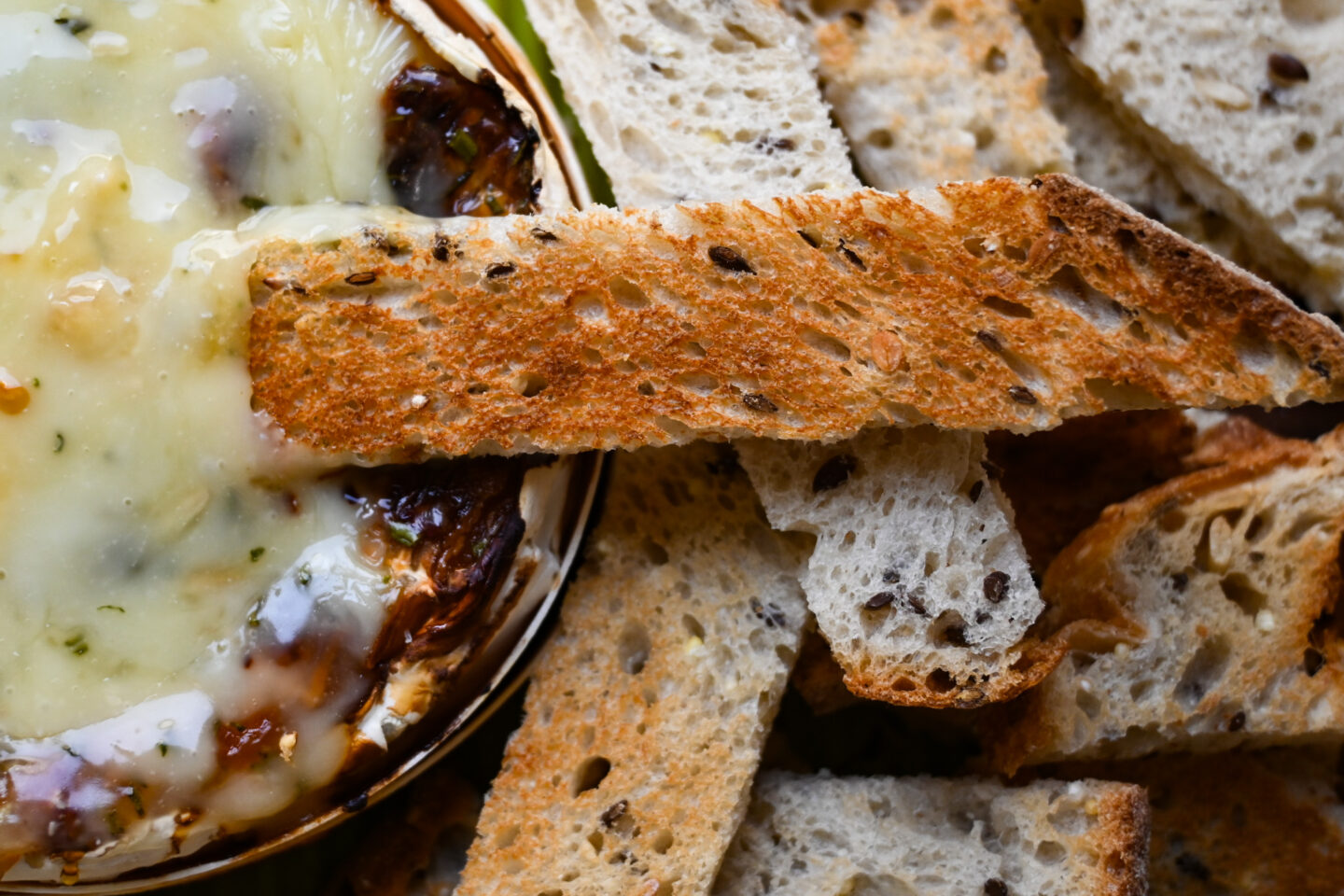 Close-up of a toast point dipped in melted, baked camembert