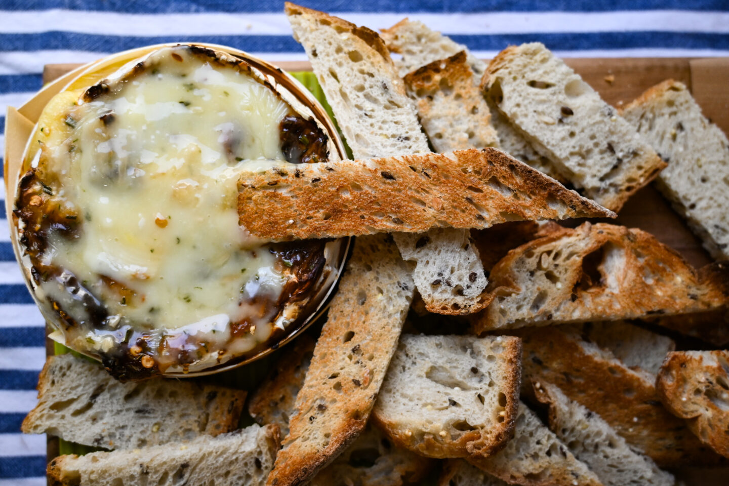 Lots of toasted bread with melted baked camembert on a board