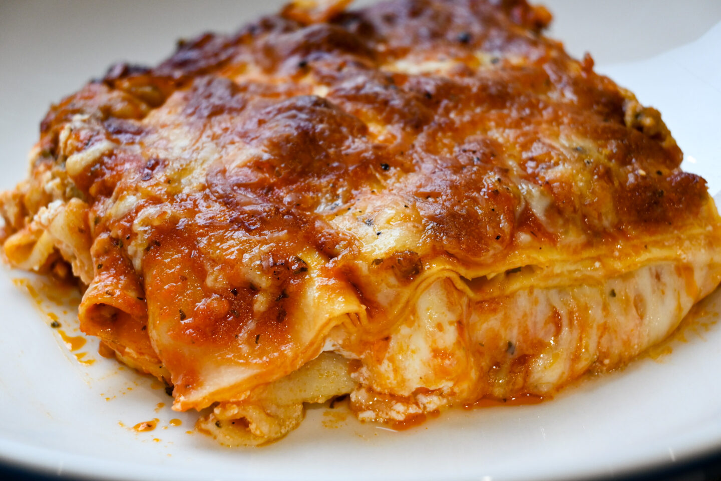 Slice of Sausage & Mint Lasagna showing oozy, melted cheese between the pasta layers